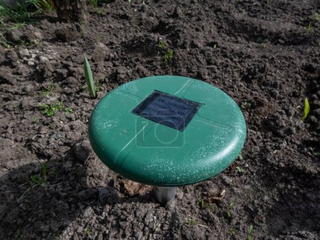 Primer plano del dispositivo ultrasónico de repelente o repelente solar en el suelo en un lecho vegetal en el jardín. Dispositivo con pitido para evitar plagas