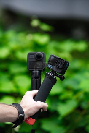 Photo for Male hand with a camera holds a tripod for shooting - Royalty Free Image