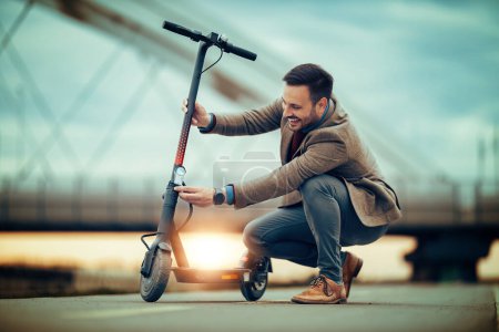 Téléchargez les photos : Jeune homme en costume conduisant son scooter à la journée ensoleillée. Concept de transport écologique. - en image libre de droit