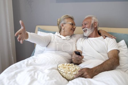 Téléchargez les photos : Couple sénior se détendre dans la chambre et regarder la télévision. - en image libre de droit