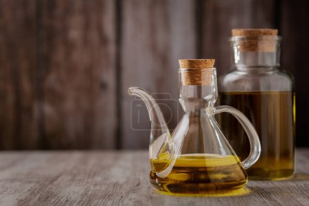 Photo for Extra virgin olive oil in a oil can and in a small bottle on a white rustic wooden table, with a wooden background. - Royalty Free Image