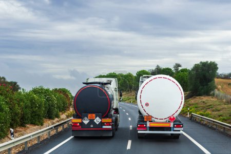 Dos camiones cargados de mercancías peligrosas, uno de líquidos contaminantes y los otros gases inflamables, paralelos en la carretera.