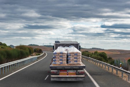 Photo for Truck loaded with bags of cement driving on a highway. - Royalty Free Image
