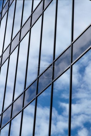 Téléchargez les photos : Façade murale en verre avec réflexion du ciel nuageux. Architecture urbaine moderne arrière-plan - en image libre de droit