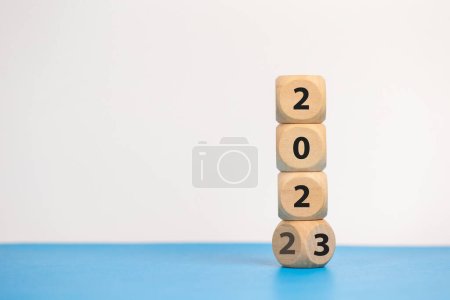 Téléchargez les photos : Cubes de blocs de bois avec un numéro 2022 changer pour 2023 fond bleu. nouvelle année 2022-2023 concept. - en image libre de droit