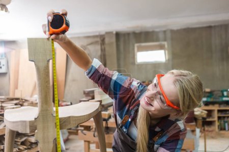 Photo for Young carpenter women using measuring tape looking wood size at workspace. craftsman profession in wood factory. professional furniture woodwork. - Royalty Free Image