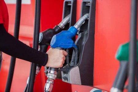 close up hand of woman holding pump nozzle for service at gas station. male employee worker fueling oil car. business energy concept.