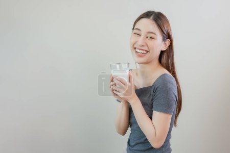 Happy asian women holding glass fresh milk. Healthy food concept. Drinks beneficial to body. Female enjoy drinking calcium lactose. Copy space use for text message.
