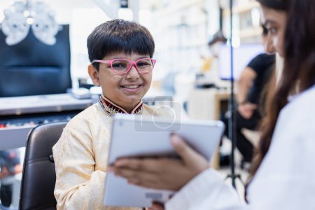 Foto de Niño indio feliz con gafas en la tienda de gafas. Chico paciente chequeo masculino iris examina clínica oftalmológica de gafas Measure. - Imagen libre de derechos