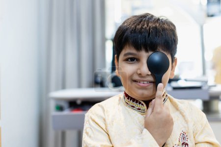 Foto de Niño indio examinando la visión chequeo visión clarividencia examina hospital oftalmológico. doctor usando oclusor para la prueba oftalmológica del ojo para el muchacho indio. - Imagen libre de derechos