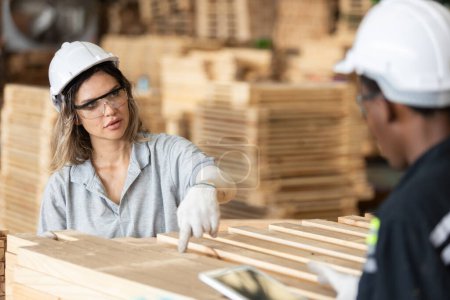 Frau in Schutzuniform und harter Hut arbeitet Qualitätskontrolle von Holzprodukten in der Werkstatt Herstellung von Holz. Tischlerin arbeitet in Holzlagerindustrie.