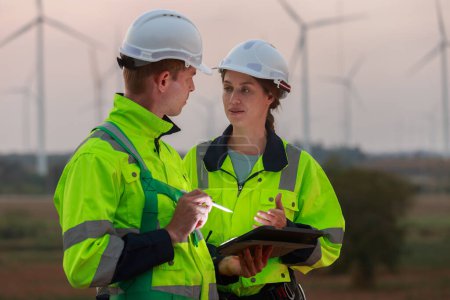 Ingenieur in Schutzkleidung mit Tablet diskutierte Plan über erneuerbare Energien in Station Energie Windenergie Turbine. Technologie zum Schutz der Umwelt reduziert globale Erwärmungsprobleme.