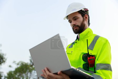 Engineer wearing safety uniform holding laptop discussed plan about renewable energy at station energy power wind. technology protect environment reduce global warming problems.