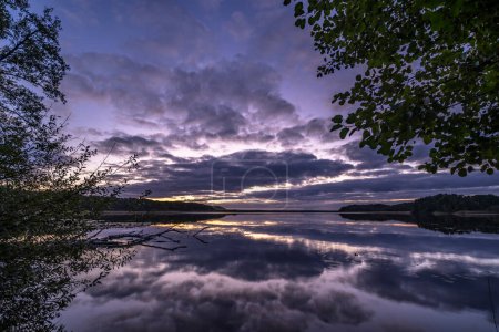 Téléchargez les photos : Magnifique coup de soleil couchant ciel sur le lac entouré d'arbres - en image libre de droit