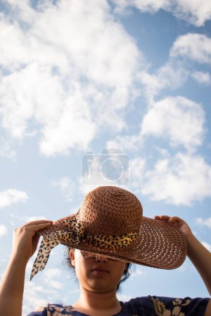 Photo for Woman with blue dress wearing a wicker hat on sunny day - Royalty Free Image