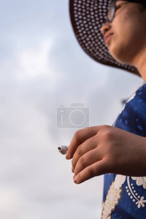 Photo for Close up of hand of woman wearing a dress and holding an earphone - Royalty Free Image
