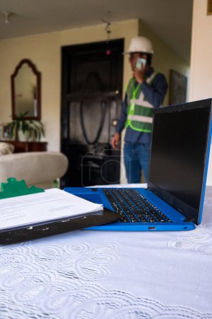 Latin construction worker man talking on phone at home