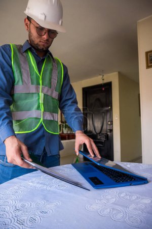 Latin construction worker man taking laptop for leaving home 