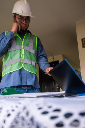 Latin construction worker man taking laptop for leaving home 