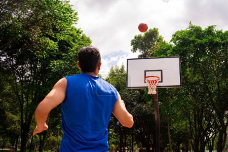 Man training basketball in court in sunny day at summer 