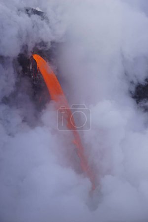 Téléchargez les photos : Hot  Lava stream flowing out of cliff into the ocean surrounded by white steam cloud - en image libre de droit