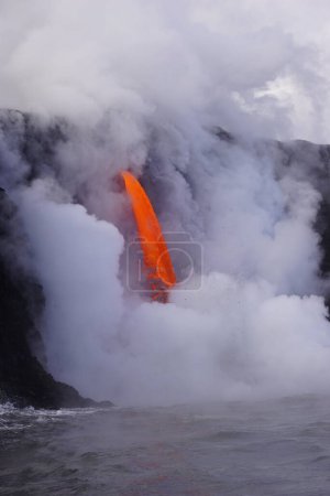 Téléchargez les photos : Lava flowing down from high cliff into the ocean - en image libre de droit