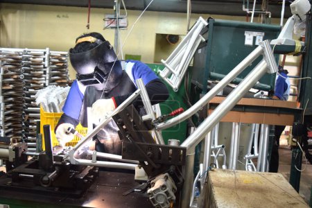 Foto de Sidoarjo, Indonesia - April 9, 2015: worker welding material the spare part on the assembly line at bicycle assembly from Indonesia Polygon in Sidoarjo, East Java, Indonesia - Imagen libre de derechos