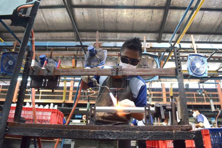 Téléchargez les photos : Sidoarjo, Indonesia - April 9, 2015: worker welding material the spare part on the assembly line at bicycle assembly from Indonesia Polygon in Sidoarjo, East Java, Indonesia - en image libre de droit
