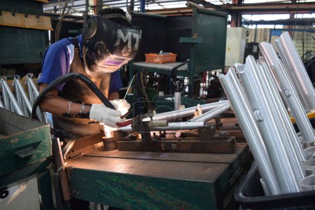 Téléchargez les photos : Sidoarjo, Indonésie - 9 avril 2015 : Le matériau de soudage des travailleurs la pièce de rechange sur la chaîne de montage à l'assemblage de bicyclettes d'Indonésie Polygon à Sidoarjo, Java Est, Indonésie - en image libre de droit