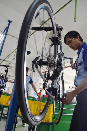 Téléchargez les photos : SIDOARJO, INDONÉSIE - 9 AVRIL 2015 : Un travailleur vérifie la chaîne de montage du vélo d'assemblage de Indonesia Polygon à Sidoarjo, Java Est, Indonésie - en image libre de droit