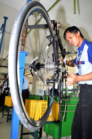Foto de SIDOARJO, INDONESIA - 9 DE ABRIL DE 2015: Trabajador verificando la línea de montaje en la bicicleta de montaje del polígono de Indonesia en Sidoarjo, Java Oriental, Indonesia - Imagen libre de derechos