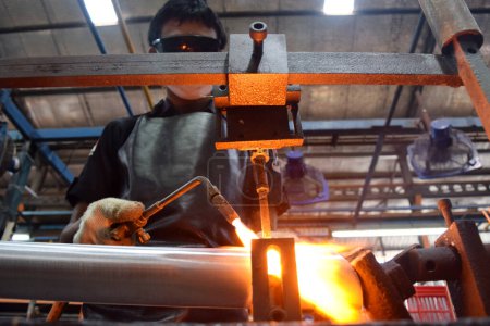 Photo for Sidoarjo, Indonesia - April 9, 2015: worker welding material the spare part on the assembly line at bicycle assembly from Indonesia Polygon in Sidoarjo, East Java, Indonesia - Royalty Free Image