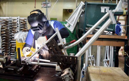 Photo for Sidoarjo, Indonesia - April 9, 2015: worker welding material the spare part on the assembly line at bicycle assembly from Indonesia Polygon in Sidoarjo, East Java, Indonesia - Royalty Free Image