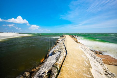"Mexico Beach, Florida USA, boasts rocky jetties framing emerald-blue waters, blending seamlessly with white sandy beaches under a serene blue sky, offering a picturesque escape."