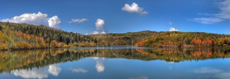 An aspen tree forest in full color is reflected in the calm water of Kolob Reservoir adjacent to Zion National Park, Uath