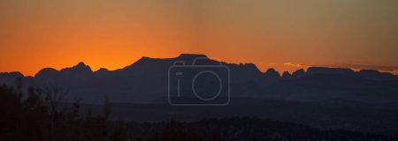 The sun sets behind the skyline of Zion National park, Utah