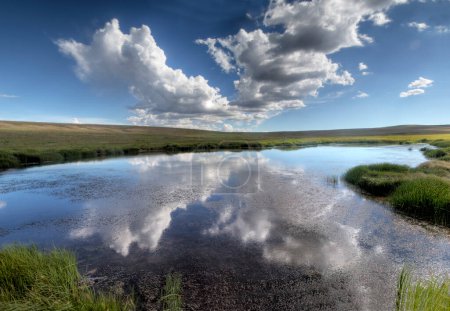 Large clouds are reflected in a small pond at Kolob Terrace in the highlands of Southern Utha