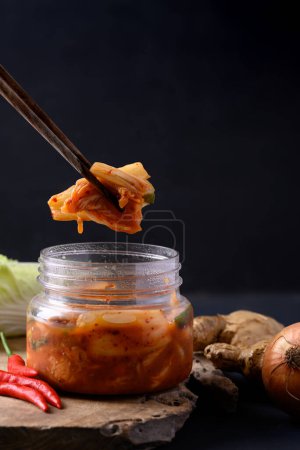 Photo for Kimchi cabbage in bowl eating by chopsticks on black background, Asian fermented food - Royalty Free Image