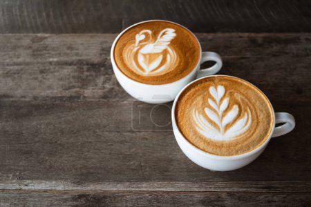 Foto de Café de arte latte con forma de cisne y árbol del corazón en taza de café sobre fondo de madera, bebida caliente - Imagen libre de derechos