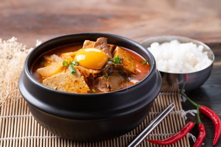 Photo for Korean food, Kimchi soup with tofu, pork and fresh egg yolk in Korean stone pot - Royalty Free Image