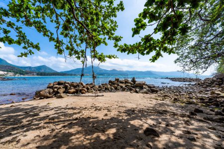 Téléchargez les photos : Une île paisible de Con Dao, le Vietnam est un paradis insulaire vietnamien. Vue côtière avec vagues, littoral, ciel clair et route, mer bleue, touristes et montagne. Concept de voyage et paysage. - en image libre de droit