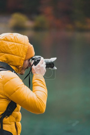 Photo for Selective focus of outdoor photographer taking landscape photos using digital camera. Side view of man holding dslr - Royalty Free Image