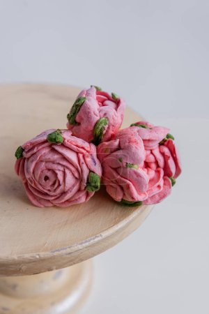 Photo for On a wooden round background lie natural marshmallows in the form of pinkroses flowers. Sweet desserts without sugar. Creative baking confectioners. Copy space, mock up. Sweet food - Royalty Free Image