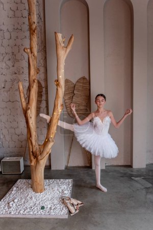 Jeune ballerine en tutu blanc avec un sourire joyeux s'amuser, capture la fantaisie de la danse, entouré par l'art rustique natures et doux, éclairage éthéré. Intérieur du loft
