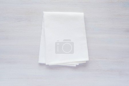 Photo for Folded in square blank cotton tea towel for design presentation, white waffle fabric kitchen towel mockup, minimal composition on white wooden background. - Royalty Free Image