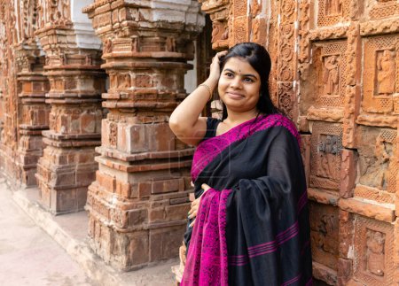 Téléchargez les photos : Une jolie indienne à saree près d'un temple en terre cuite du Bengale occidental - en image libre de droit