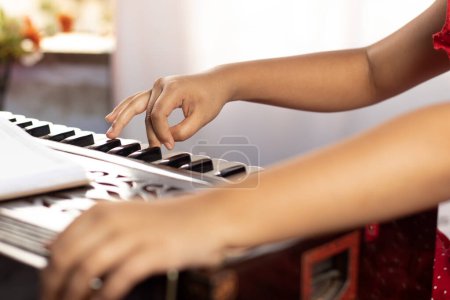 Photo for Hands of an Indian girl child plying harmonium with selective focus on white background - Royalty Free Image