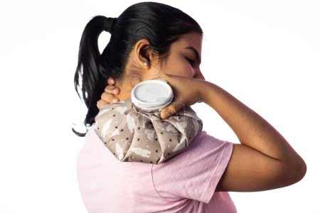 Una mujer india usando bolsa de agua caliente para aliviar el dolor de hombro sobre fondo blanco