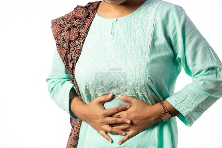 An Indian woman holding her belly for pain showing painful expression on white background