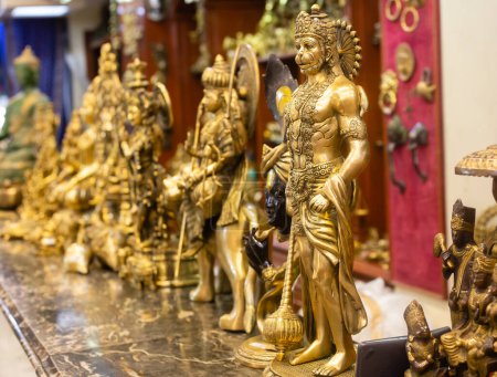 ídolo de bronce de lord Hanuman junto con otras estatuas que se venden en una tienda de mercado india